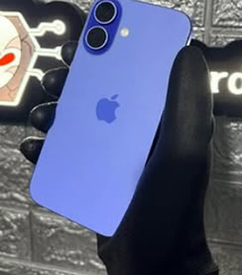 iPhone 16 azul ultramarino segurado com luva em frente ao letreiro da loja