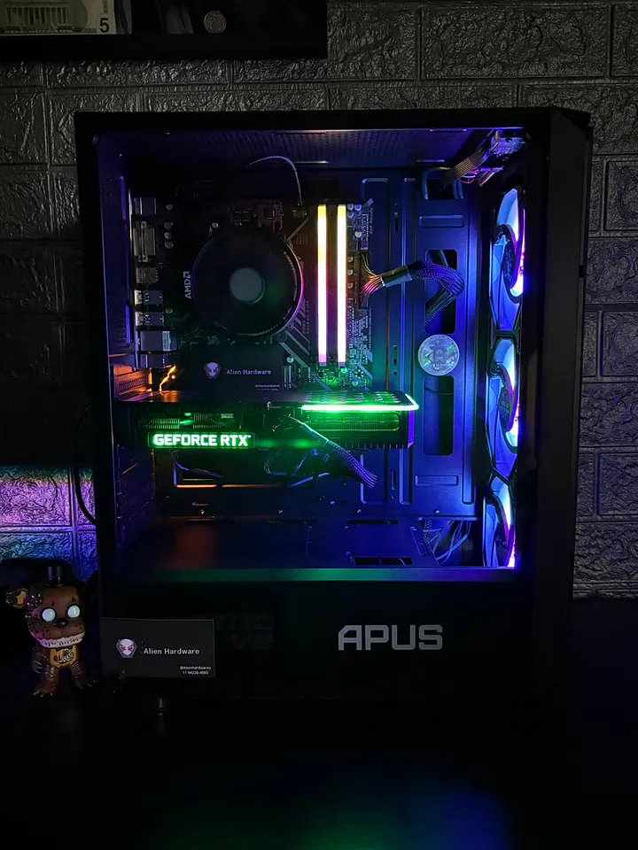 PC gamer com processador AMD, placa de vídeo GeForce RTX e memórias RGB, em gabinete preto com fans azuis